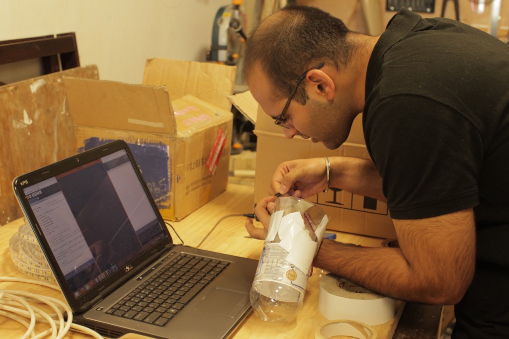 Man using soldering iron behind laptop