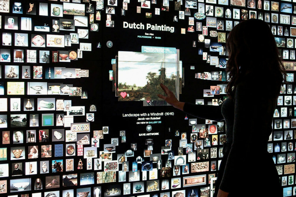 Woman interacts with information provided in the ARTLENS project through a large interactive touch screen